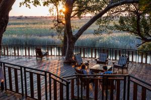 two people sitting in chairs on a deck next to a lake at Namushasha River Camping2Go in Kongola