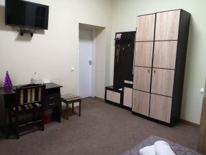 um quarto com uma secretária, um armário e uma televisão em Orange Hotel em Lviv
