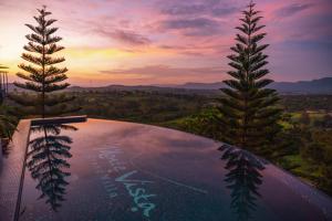 a pool with two trees and a sunset in the background at Monte Vista Chalet Khaoyai in Ban Nong Song Hong