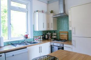 cocina con armarios blancos, fregadero y ventana en Seagulls Nest Beachfront Apartment With 3 Bedrooms en Hastings