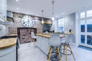 a kitchen with a brick wall and a clock on the wall at Augustus House in Chester
