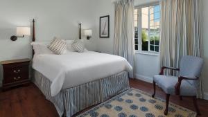 a bedroom with a bed and a chair and a window at Oxford House in Hamilton