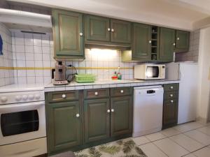 una cocina con armarios verdes y electrodomésticos blancos en Les Lavandines -Coquette Maison de Vacances - 400 m de la plage - Grande Terrasse - 2 chambres - 2 salles de bain - Tout confort en Argelès-sur-Mer