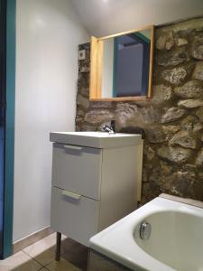 ein Badezimmer mit einem Waschbecken und einem Spiegel an einer Steinmauer in der Unterkunft Au pti fayt in Barbençon