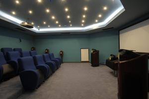 une salle de conférence avec des chaises bleues et un podium dans l'établissement Roxani Country House Resort, à Maroneia