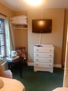 a bedroom with a dresser and a tv on the wall at Railway Bar Apartment in Poyntz Pass