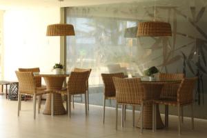 uma sala de jantar com cadeiras e mesas de vime em Lindo Apartamento pé na areia com serviço de limpeza em Lauro de Freitas