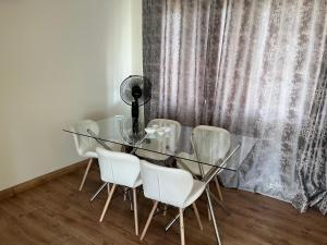 une table et des chaises en verre dans une pièce avec rideau dans l'établissement House 210 holiday rentals, à Alberton