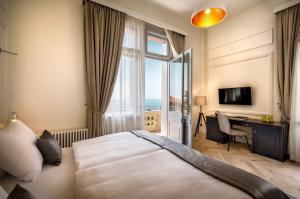 a bedroom with a bed and a desk and a window at Hotel Imperial - Liburnia in Opatija