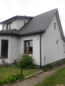 een wit huis met een zwart dak bij Pokoje Kościelna 6 in Supraśl