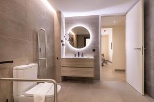 马拉加Home Art Apartments Soho的带水槽、马桶和镜子的浴室