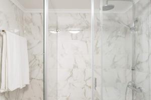 a bathroom with a shower with white marble walls at Beach House Ericeira in Ericeira