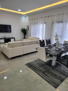 een woonkamer met een bank en een tafel en stoelen bij Résidence Adja Cogna Appartement de luxe au virage in Dakar