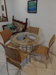 uma sala de jantar com uma mesa de vidro e cadeiras de vime em Apartamento de Luxo acesso a Praia Grande e Praia do Tenório para 6 pessoas em Ubatuba