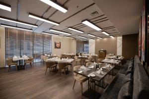 um restaurante com mesas e cadeiras num quarto em Swiss-Belinn Sharq, Kuwait em Kuwait