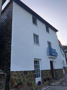 a white house with a blue balcony on it at Casa da Carvalha - Ádela in Açor