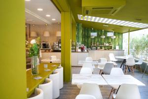 um restaurante com mesas e cadeiras brancas e uma cozinha em Hotel Rex em Gabicce Mare