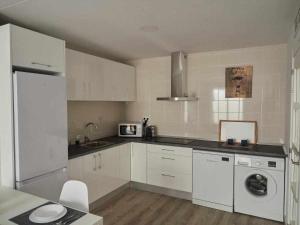 a kitchen with white cabinets and a washer and dryer at San José Apartamentos Turísticos Karlie in Albacete