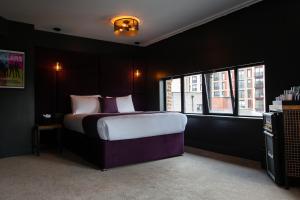 ein Schlafzimmer mit einem großen Bett und zwei Fenstern in der Unterkunft The Baltic Hotel in Liverpool