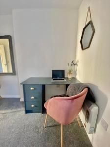 魯吉利的住宿－Chase Heights，一张带粉红色椅子的桌子和一张带笔记本电脑的桌子