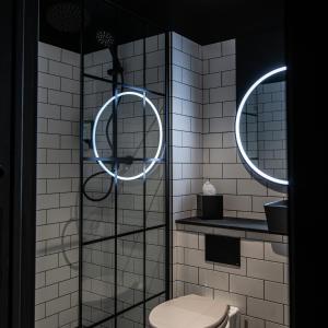 uma casa de banho com WC e 2 espelhos redondos em The Baltic Hotel em Liverpool