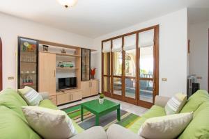 a living room with a green couch and a table at Dulcamara con piscina by Wonderful Italy in Soiano del Lago
