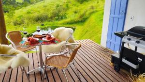 a table and chairs on a deck with a grill at Chalé do Lago super Luxo in Cunha