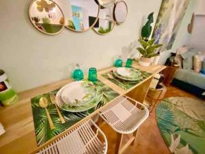 a dining room table with plates and mirrors on the wall at Escale Tropicale à Blois in Blois