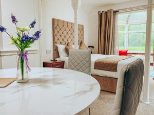 クローリーにあるTrivelles Waterhall Country Gatwick Hotel & airport parkingのベッドと花のテーブルが備わるホテルルームです。