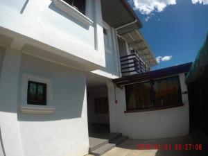 a white house with a balcony and a staircase at AA TRAVELLERS PAD in Laoag