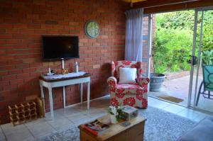a living room with a chair and a tv on a brick wall at The Red Wine Cottage in Stellenbosch