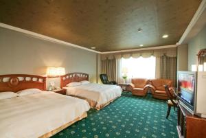 ein Hotelzimmer mit zwei Betten und einem Flachbildfernseher in der Unterkunft F Hotel Tainan- Pet-friendly in Tainan