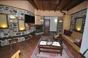 sala de estar con sofá y pared de piedra en Pasithei, en Karpenisi
