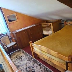 an attic bedroom with a bed and a chair at La Clé des Champs in Les Fourgs