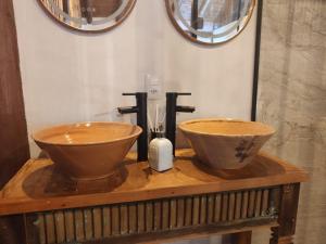 two wooden bowls on a wooden table with two mirrors at Chalé Arara super Luxo in Cunha