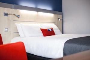a hotel room with a bed with a red pillow on it at Holiday Inn Express Toulouse Airport, an IHG Hotel in Blagnac