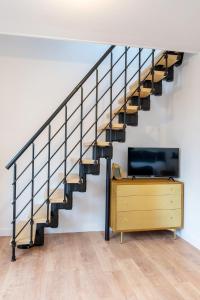 uma escada numa casa com uma televisão e uma cómoda em Le Magnifique Appart'Hotel Le Gatsby em Saint-Quentin