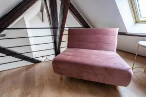 Zimmer mit einem rosa Stuhl im Dachgeschoss in der Unterkunft Le Magnifique Appart'Hotel Le Gatsby in Saint-Quentin