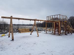 a playground in a snow covered field with a swing at Уютный домик в деревне in Privolzhsk