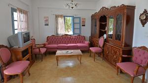 a living room with a pink couch and pink chairs at Maistrali Studios in Diafani
