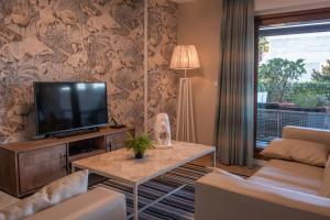 uma sala de estar com uma televisão de ecrã plano e um sofá em Apartamento Bajo en Isla de la Toja em Isla de la Toja