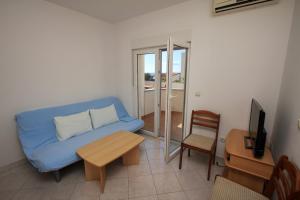 uma sala de estar com um sofá azul e uma mesa em Apartments Dubrovnik Two em Povljana