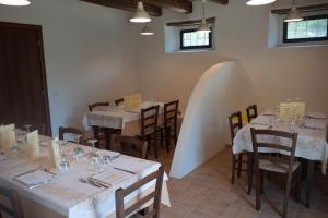 a dining room with white tables and chairs and windows at Agriturismo Mirasole in Predappio