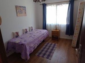 a bedroom with a bed with a purple blanket and a window at Hermosa casa en Ocean Park in Ocean Park