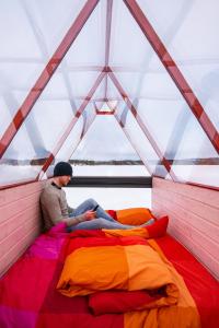a man sitting on a bed in a tent at Lake Inari Mobile Cabins in Inari