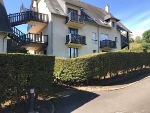 un bâtiment avec des buissons devant lui dans l'établissement Résidence le Manoir du Mont Canisy Piscine & Tennis, à Deauville