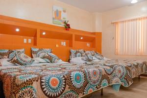 two beds in a bedroom with an orange wall at Hotel Livingston Inn in Guayaquil