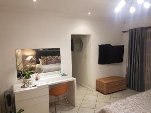 a bedroom with a sink and a mirror and a bed at Roosboompies Guest Suite in Centurion