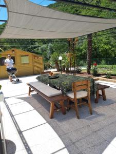 un patio con una mesa y bancos bajo un dosel en La Meridiana, en Frontone