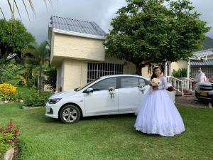 une femme en robe blanche debout à côté d'une voiture blanche dans l'établissement Alojamiento Rural Casa de Campo Erika Sofia, à Rivera